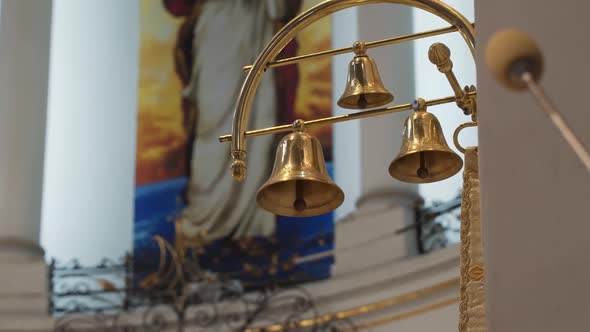 Small Golden Bells Hang on Golden Pendant in Interior of the Church