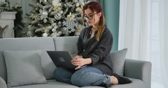 Wide Shot Portrait of Tired Confident Woman Closing Laptop with Christmas Tree at the Background