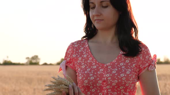 A Girl Holds a Sheaf of Wheat, Against the Background of a Beautiful Sunset in a Field, During