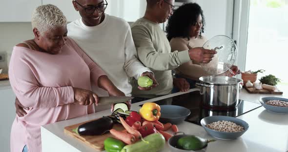 Happy black family having fun cooking together inside kitchen at home