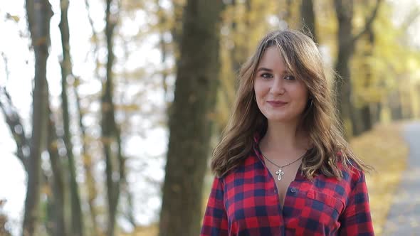 Beautiful brunette girl walks in the autumn park