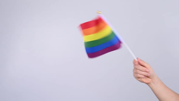 A Woman is Waving a Small Rainbow Flag on a White Background