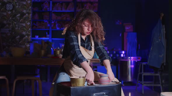 Woman with Curly Hair Taking Off a Pot From the Potter's Wheel