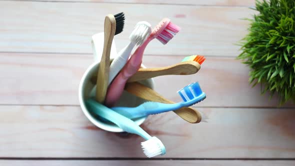 Colorful Toothbrushes in White Mug Against a Wall