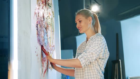 Blond Woman is Smiling While Smearing Paint with Her Hands