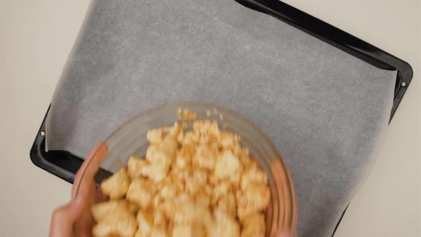 Top view of woman hands with cauliflower on tray for baking. Housewife cooking healthy meal