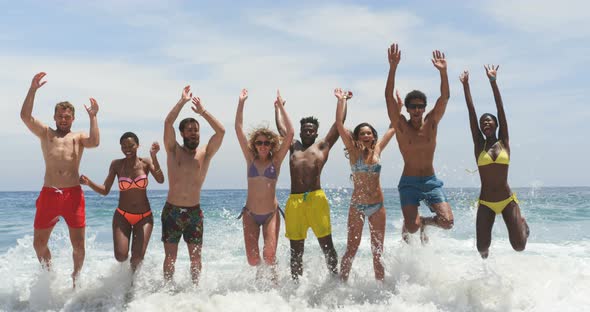 Front view of mixed-race friends jumping together on the beach 4k