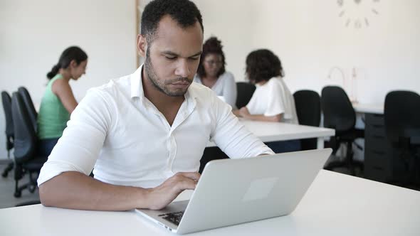 Serious Young Man Typing on Laptop.