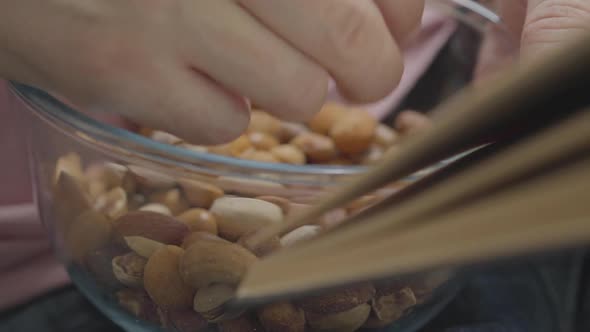 Hand of the Man Eating Nuts From Bowl While Reading Book at Home