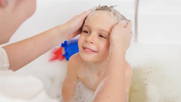 Closeup Portrait of Mother Washing Her Little Son's Head with Shampooo in Bath