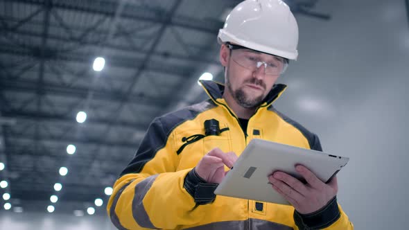 Engineer In Helmets With Tablet Device And Big Paper Drawings Discussing