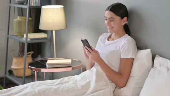 Smartphone Use By Young Latin Woman in Bed 