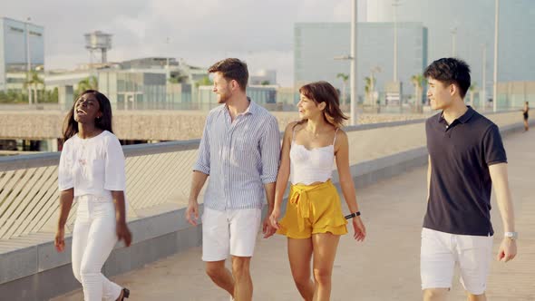 Four Happy Diverse Friends Walking Along Waterfront Chatting and Having Fun