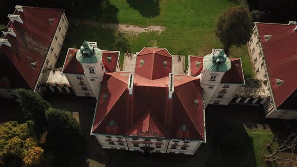 AERIAL front view of Castle. Flight over beautiful castle, located in landscape park with green tree