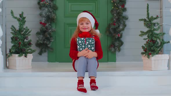 Joyful Smiling Toddler Child Girl Kid Sitting at Decorated House Porch Holding One Christmas Box