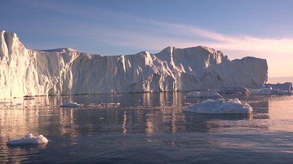 Antarctica. Cruise trip. Sailing along a huge glacier, which is illuminated by the sunset rays.