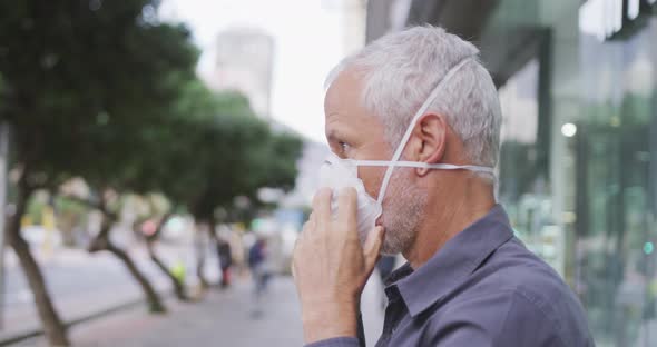 Caucasian man out and about in the street putting on a face mask against coronavirus