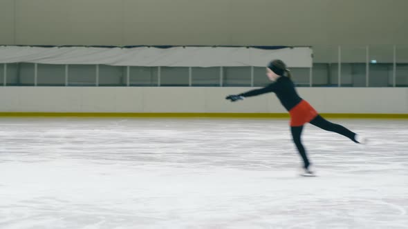 Girl sliding on ice rink, jumping and circling around herself