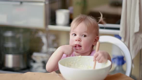 Little Cute Funny Girl Licking the Dough From Her Finger Helping Mother Prepare Pie Cake in Kitchen