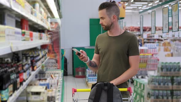 Shopping in Supermarket Man is Viewing List of Buying in Phone