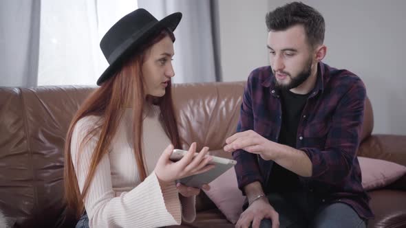 Young Cute Caucasian Woman Irritating As Her Husband or Boyfriend Explaining How To Use Tablet