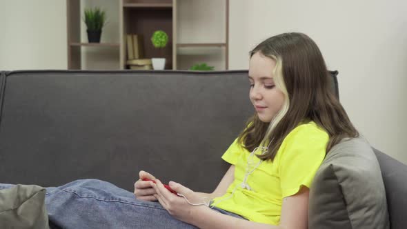 Happy Teenage Girl Wearing Headphones Watching a Video on Her Smartphone