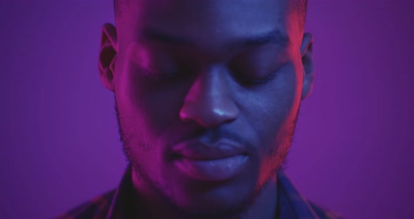 Close Up Studio Portrait of Handsome African American Man Raising Face to Camera in Neon Lights Slow