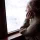Woman in Old Age Stands at the Window and Looks Alone Into the Distance - VideoHive Item for Sale