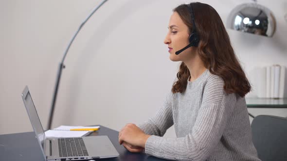 Smiling Young Saleswoman in a Headset is Holding the Phone Conversation