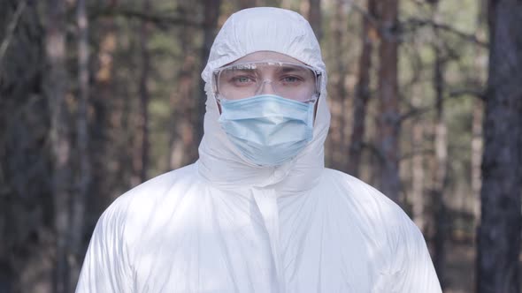 Portrait of Young Caucasian Man in Protective White Clothing, Eyeglasses and Face Mask Standing in