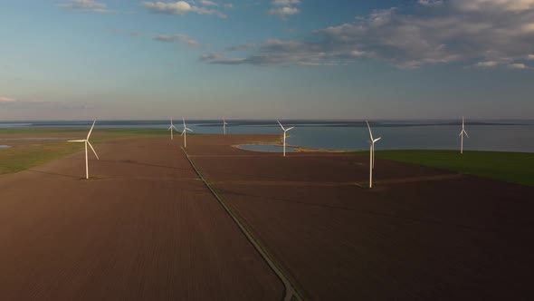 Aerial View of Wind Turbines and Agriculture Field Near the Sea at Sunset