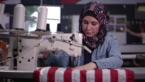 Woman wearing headscarf sewing American Flag
