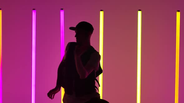 Young Man Dancing Hip Hop Against the Background of Bright Neon Lights