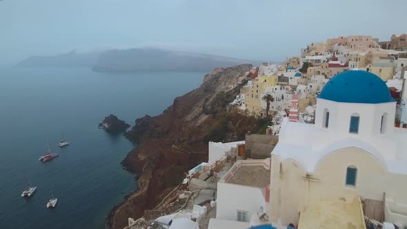 Flying over famous blue dome church in Oia on Santorini Island in Greece