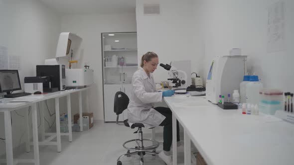 Female Medic in Uniform Working with Microscope Making Analysis at Laboratory Office