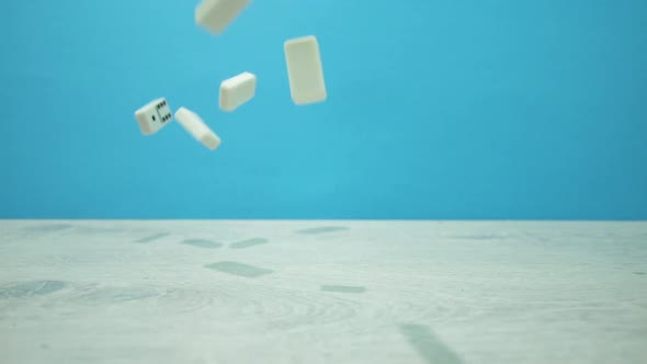 Slow Motion Shot of White Dominoes Fall on a Aquamarine Background