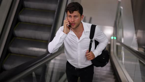 Businessman Speaking on Smartphone on Escalator