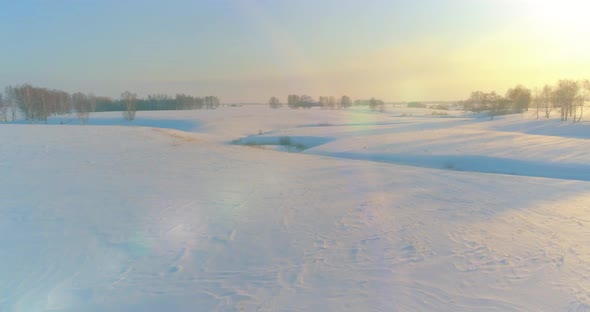 Aerial View of Cold Arctic Field Landscape Trees with Frost Snow Ice River and Sun Rays Over Horizon