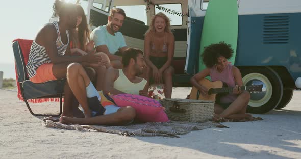 Young adult friends sitting by a camper van at a beach 4k