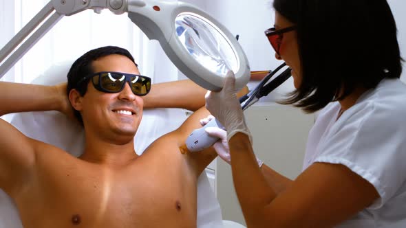 Doctor performing laser hair removal on male patient skin