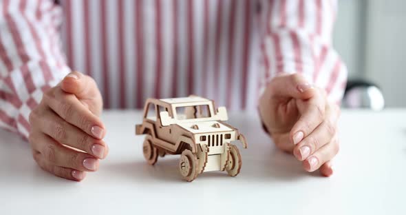 Insurance Agent Hands Hugging Wooden Toy Car Closeup  Movie Slow Motion