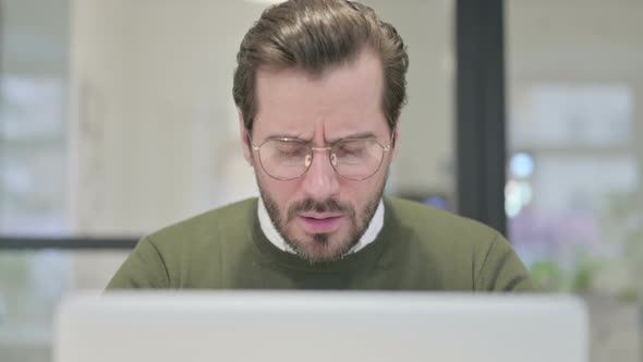 Close Up of Young Businessman Coughing While Using Laptop