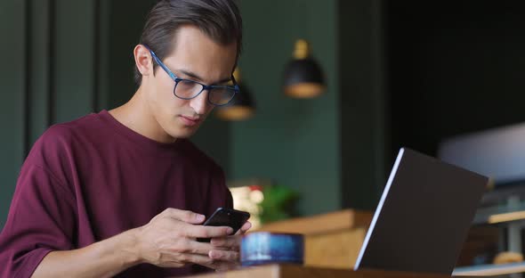 Serious Young Businessman Using Phone at Coffee Shop Checking Messages