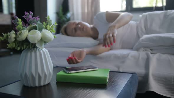 Sleepy Woman Turning Off Mobile Alarm Clock