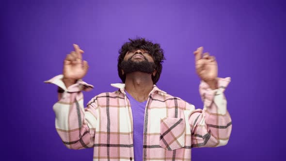 African American Guy Looking Up with Crossed Fingers for Luck Hoping for Something