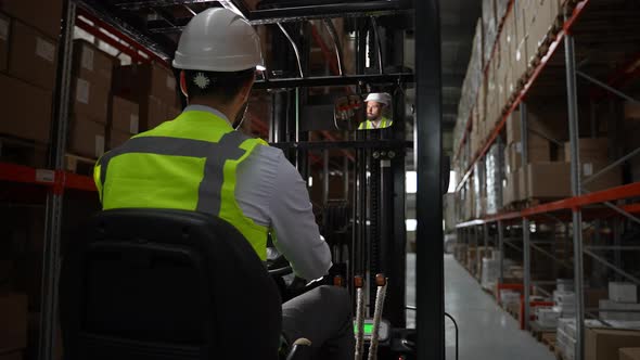 Male Worker Driving Forklift Around Storehouse