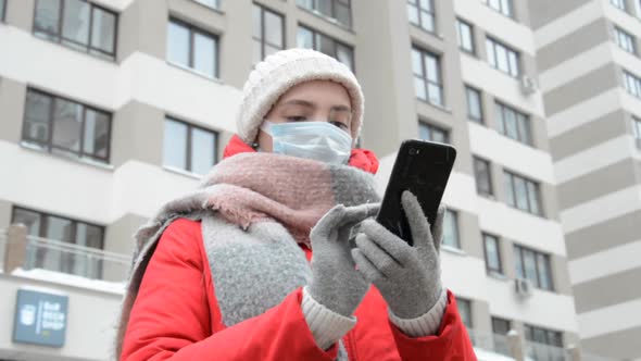 Girl in Protective Mask and Gloves Using Black Smartphone