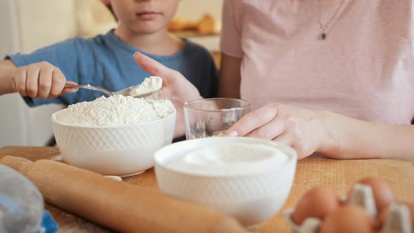 Closeup of Little Son Helping Mother Pouring Flour in Bowl for Making Biscuit or Dough