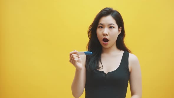 Impatient Young Asian Woman Looking at the Pregnancy Test Waiting for Results. Family Planing and