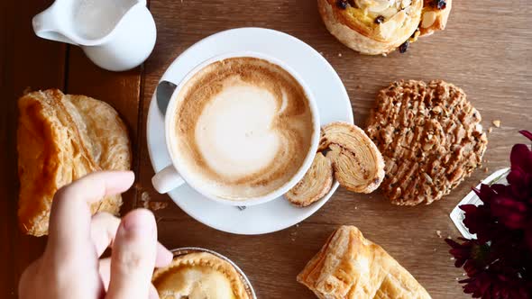 Man Hand Take a Cup of Coffee From Wooden Table with Baked Pastry Breakfast
